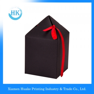 Geschenkpapierbox mit schwarzem Kreuz und roter Schleife 