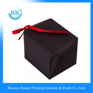 Geschenkpapierbox mit schwarzem Kreuz und roter Schleife 